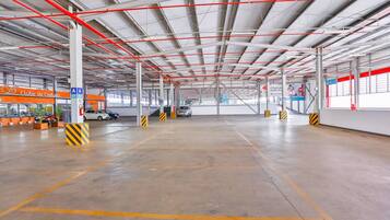 Amplio estacionamiento interior con espacios delimitados y un techo alto con vigas rojas.