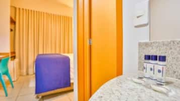 Een hotelkamer met een bed, een badkamer met toiletartikelen en een raam met gordijnen.