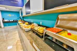A buffet with various food items including fruits, vegetables, and a variety of dishes.