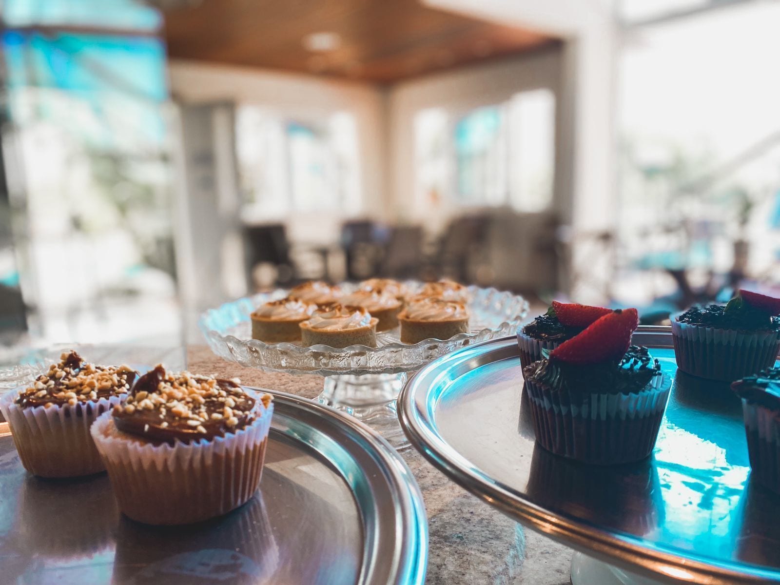 A variety of desserts on a glass serving tray in a well-lit room with a modern interior.