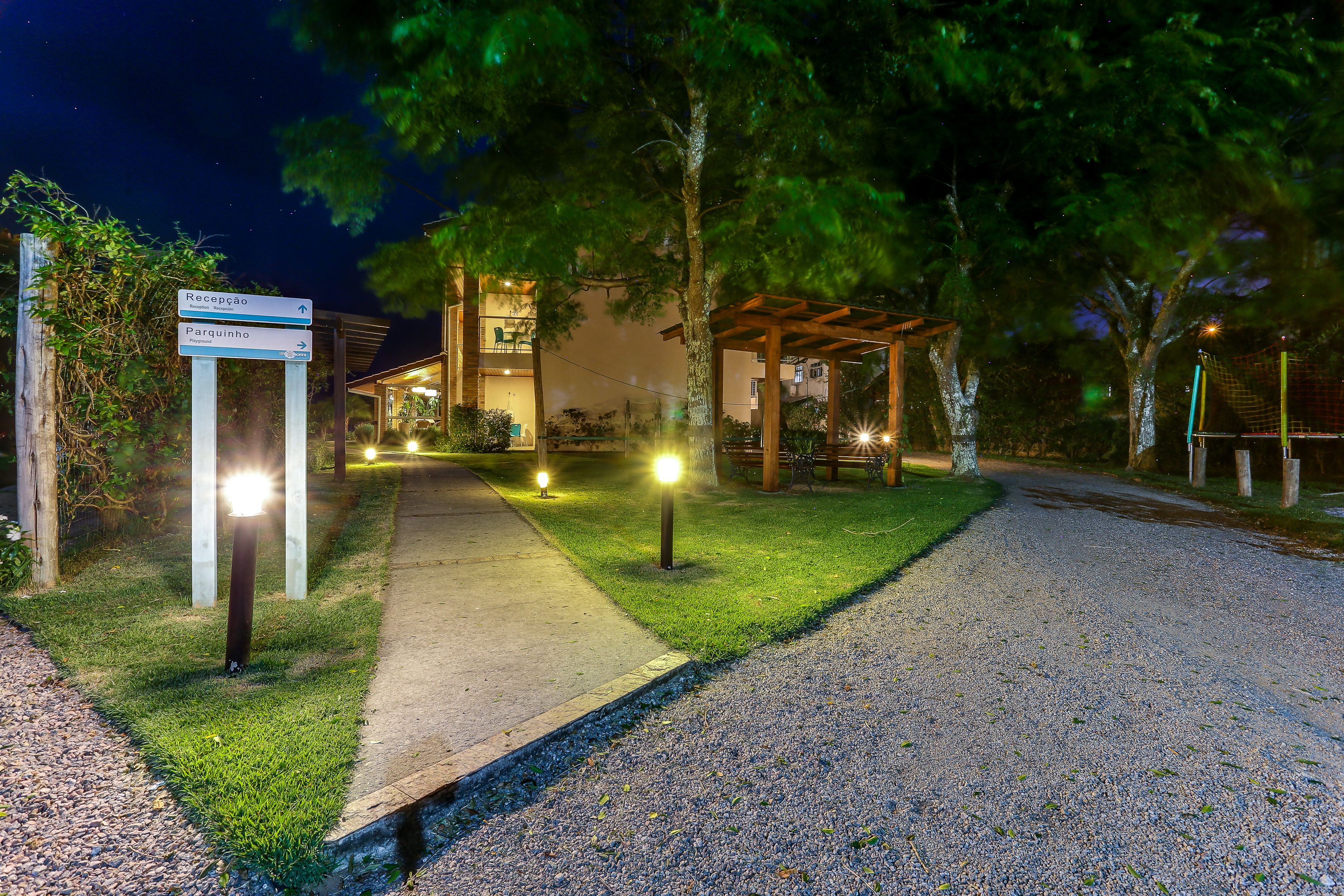 A well-lit pathway leading to a building with reception and parking signs.