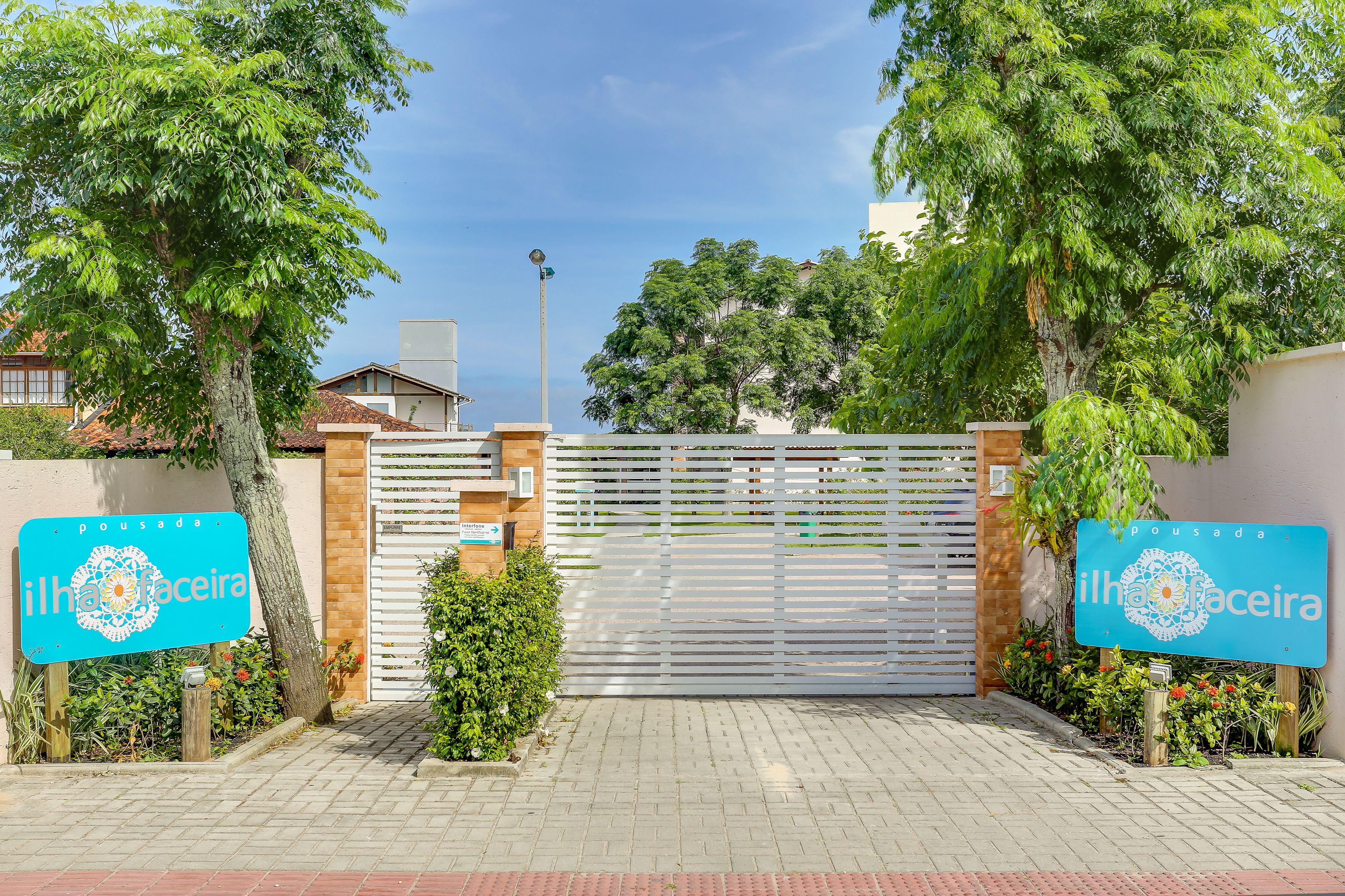 A gated entrance with a sign reading "ilha da faceira" and a decorative emblem.