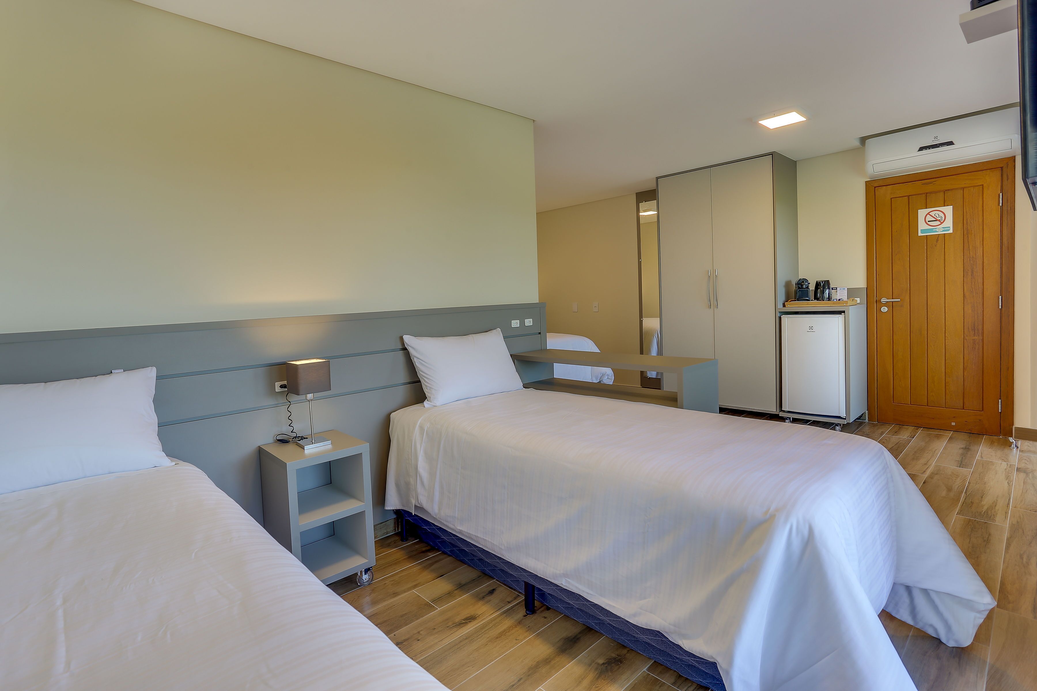 Una habitación de hotel con dos camas, un escritorio, un armario y una kitchenette.