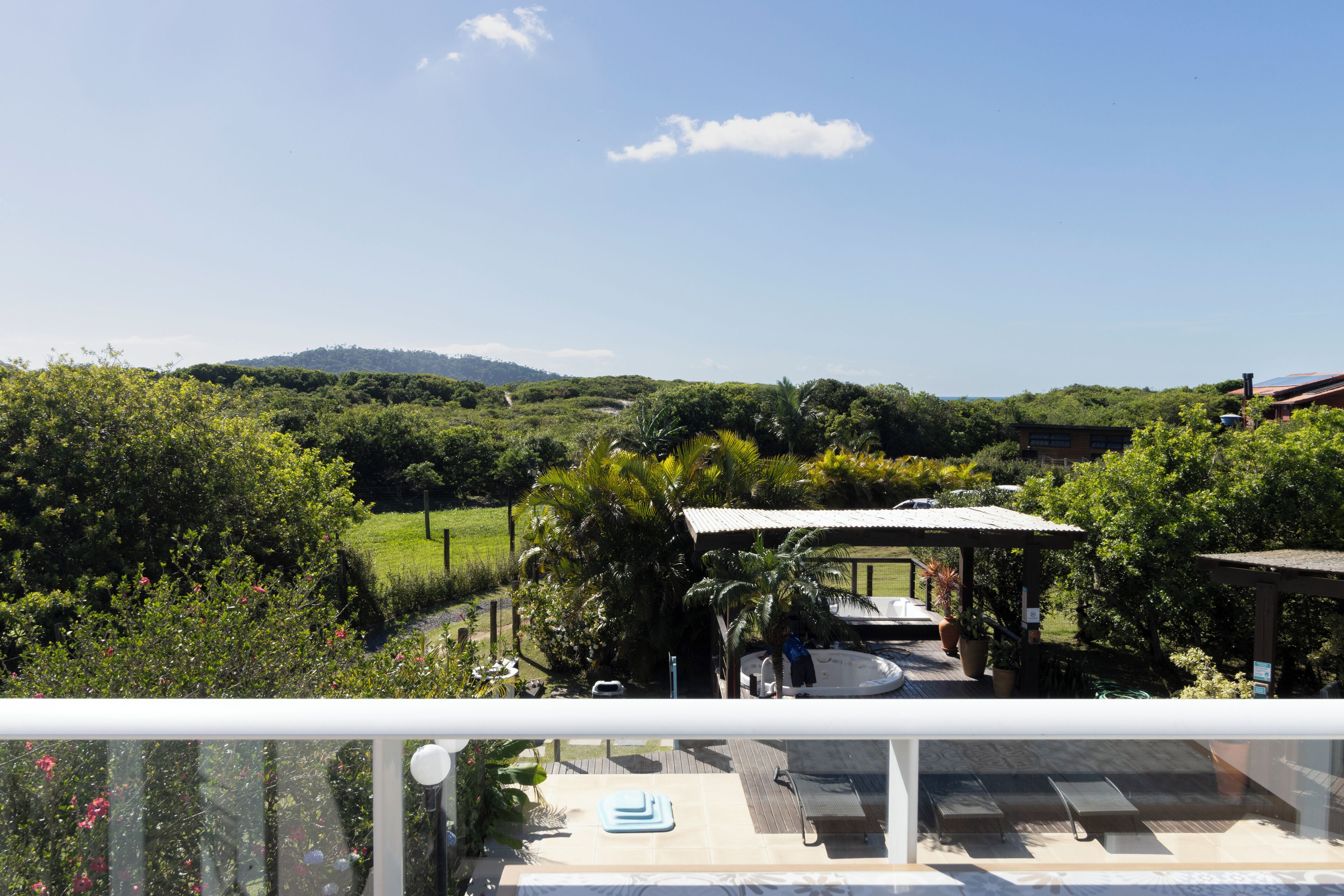 Un balcon donnant sur un jardin luxuriant, une piscine et un kiosque.