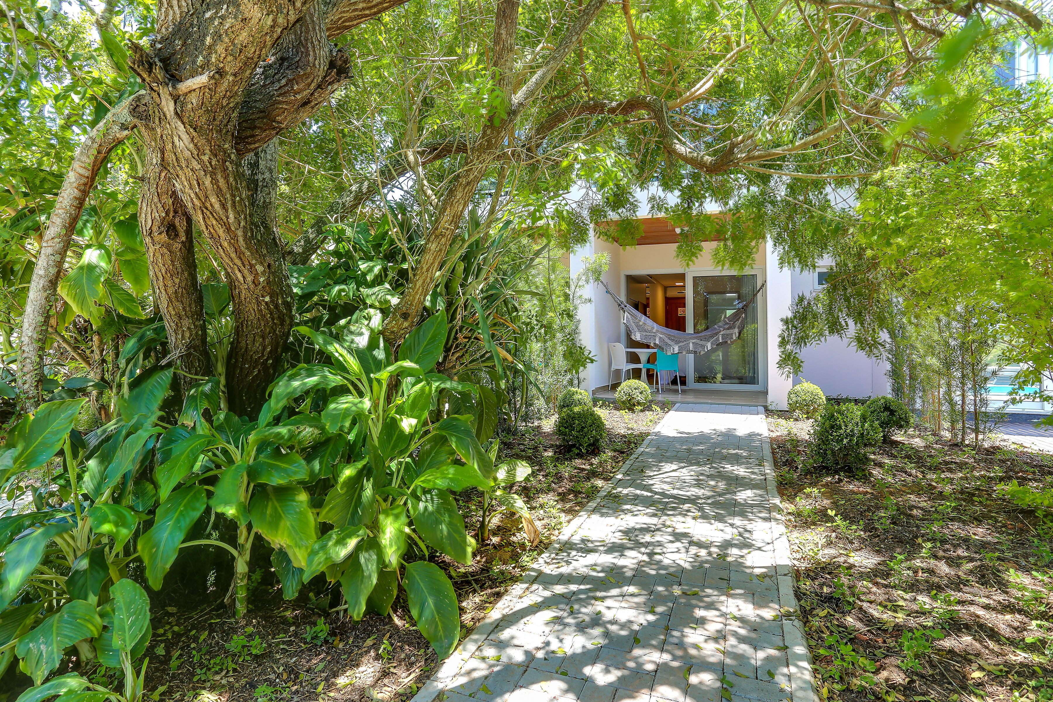 A pathway leading to a building with a hammock and a chair outside.
