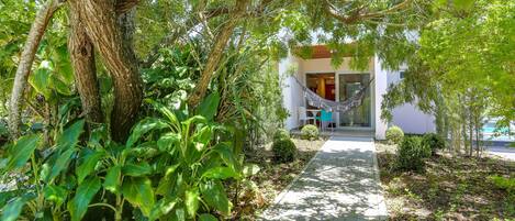 A pathway leading to a building with a hammock and a chair outside.