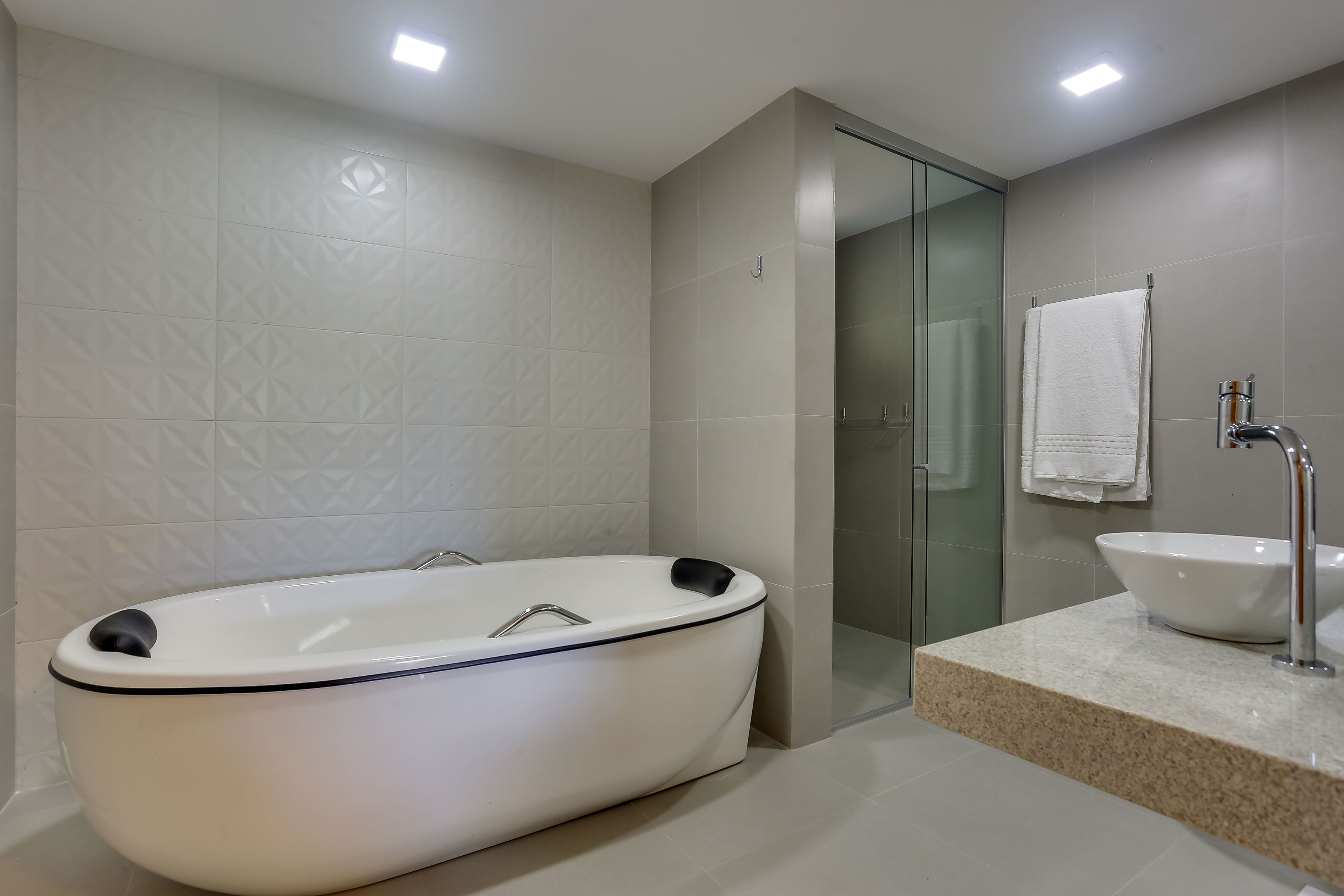 A modern bathroom with a freestanding bathtub, a glass shower enclosure, and a sink with a marble countertop.