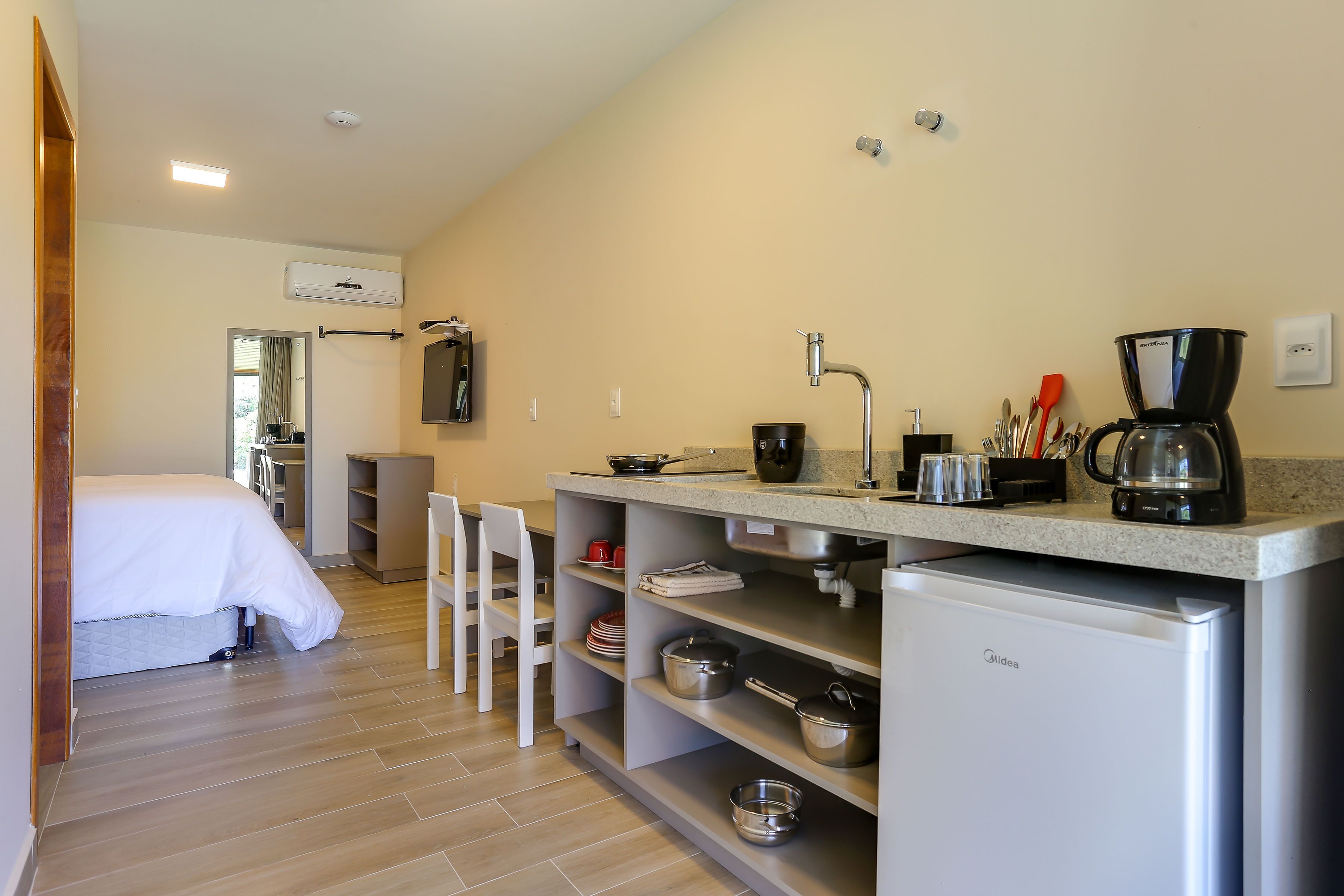 A compact kitchen with a refrigerator, coffee maker, and various utensils.