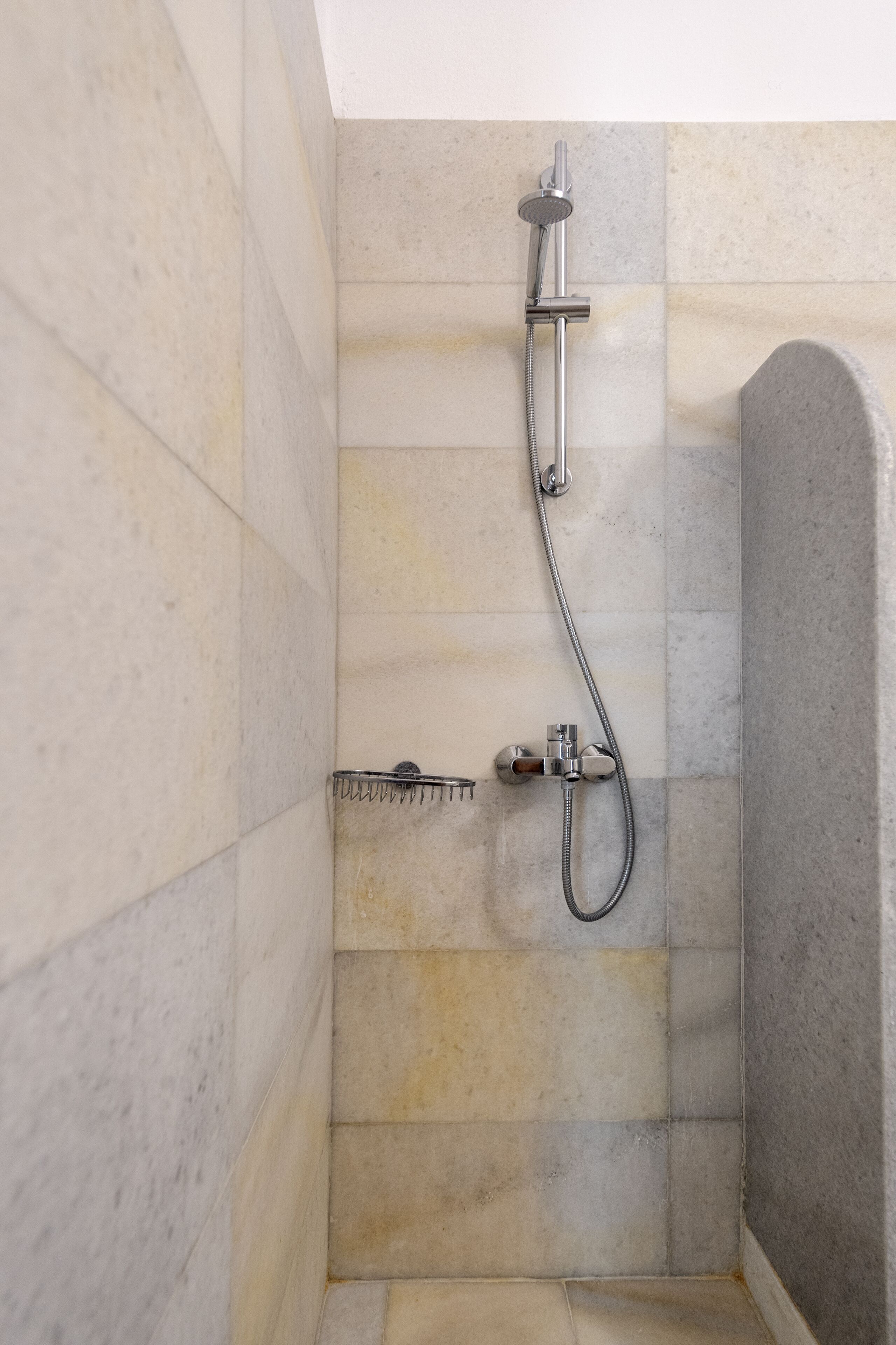 Ein Duschbereich mit Handbrause und Armatur an der Wand.