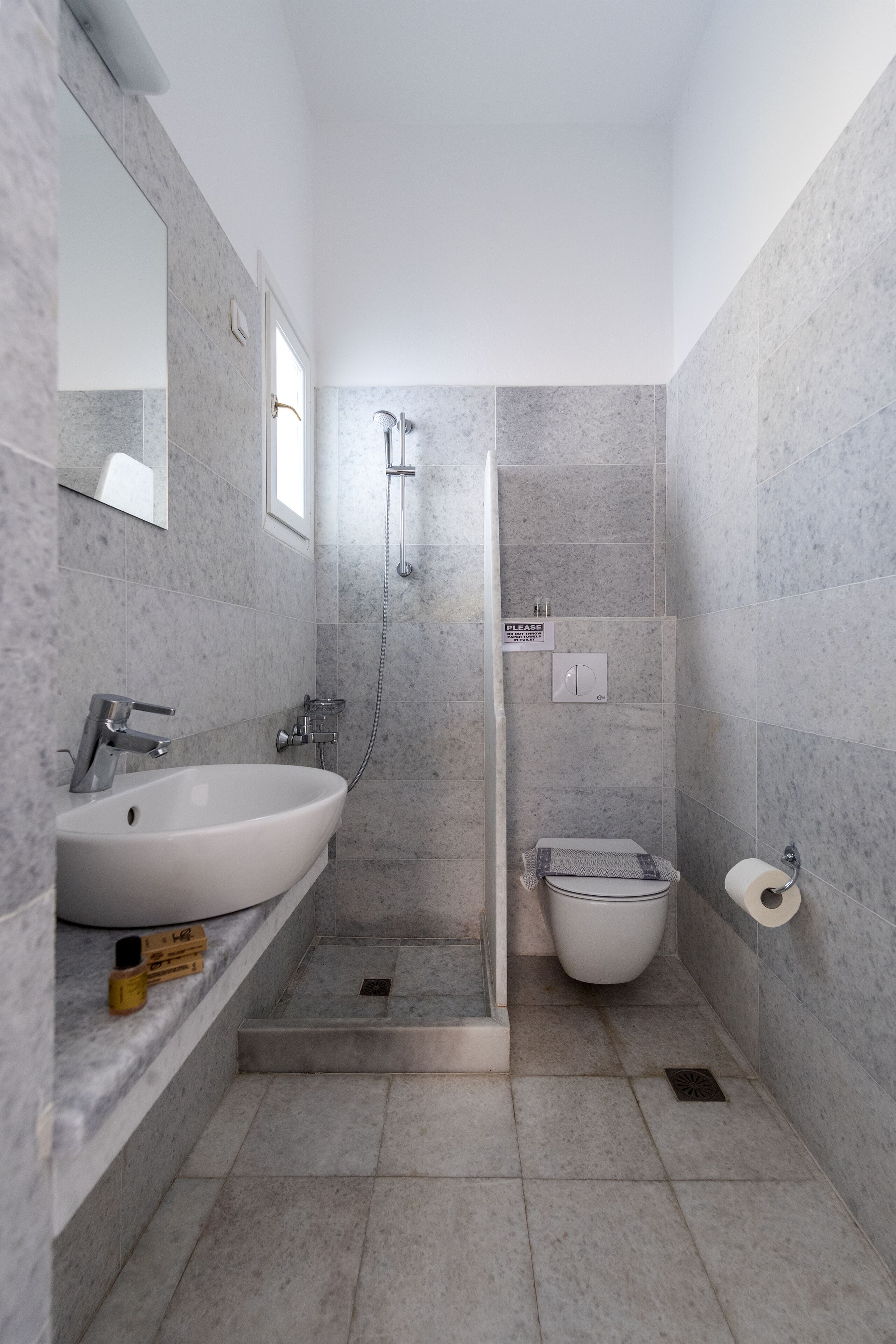 Une salle de bain avec un lavabo blanc, un miroir, un espace douche et des toilettes.