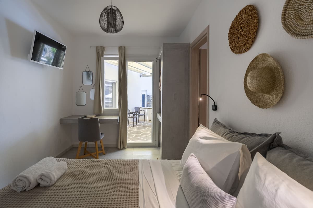 A modern hotel room with a bed, a desk, and a view of the outdoor area.