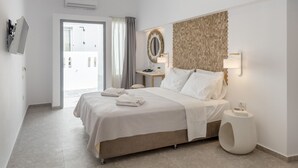 Habitación de hotel moderna con una cama grande, una mesita de noche con lámpara, un espejo en la pared y vistas al exterior.