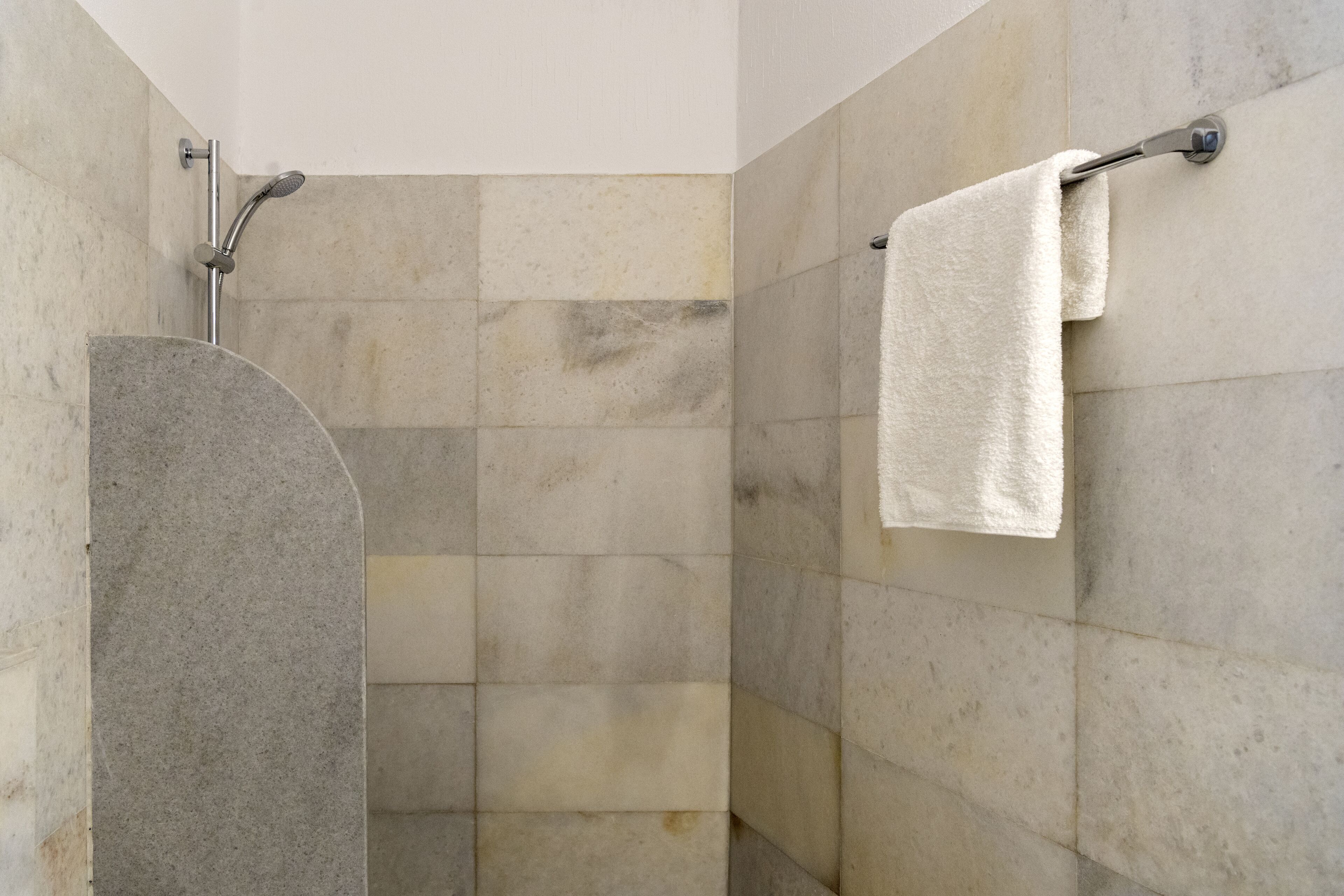 A shower area with a curved shower enclosure and a towel rack with a towel.