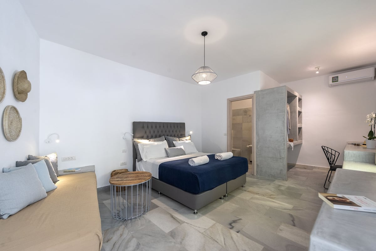 A modern bedroom with a bed, bedside tables, a hanging light fixture, and a wardrobe.