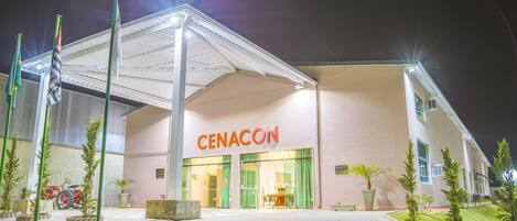 A hotel entrance with a covered walkway, a sign reading "CENACON," and a red tractor parked outside.