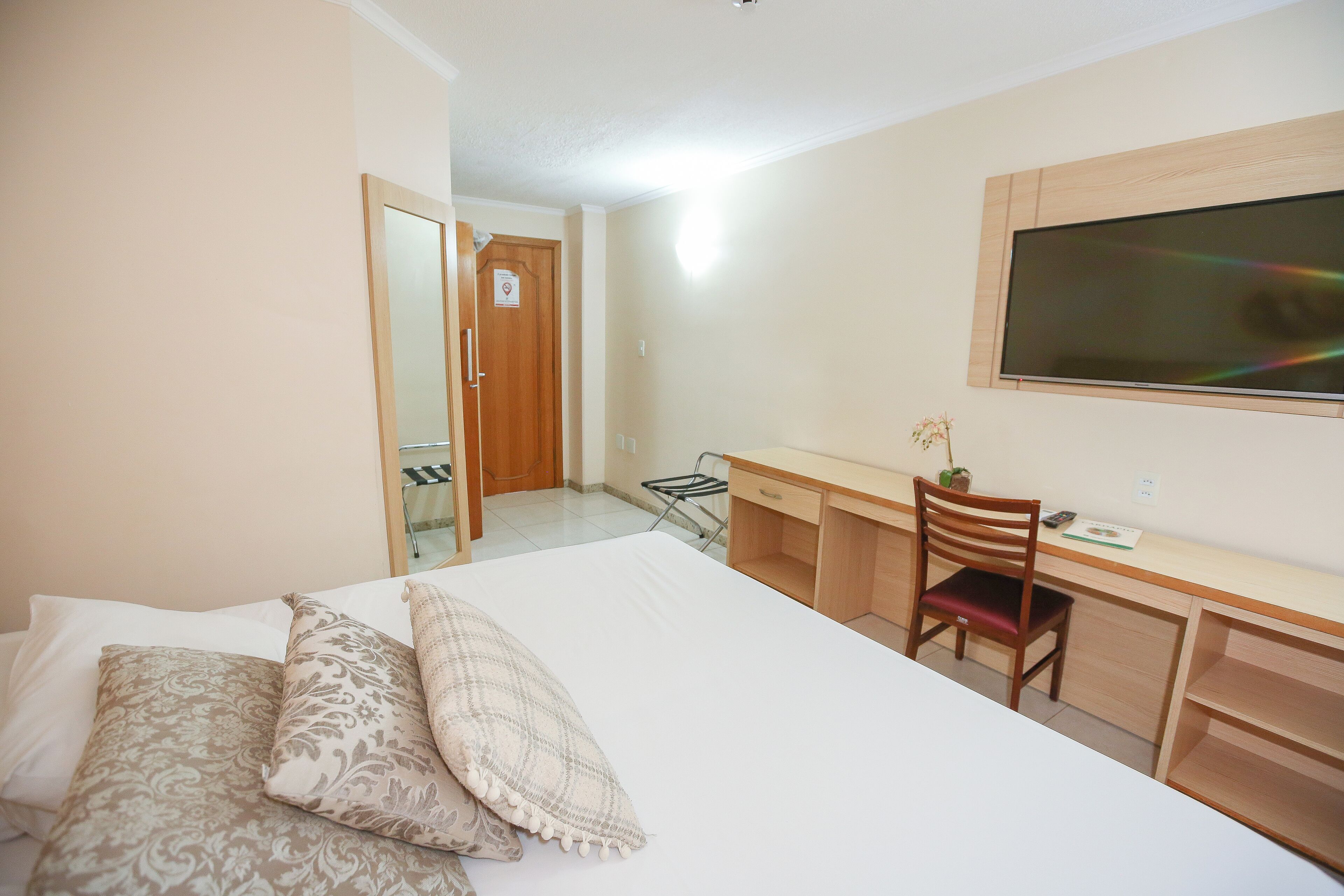 Un dormitorio con cama, escritorio y televisor.