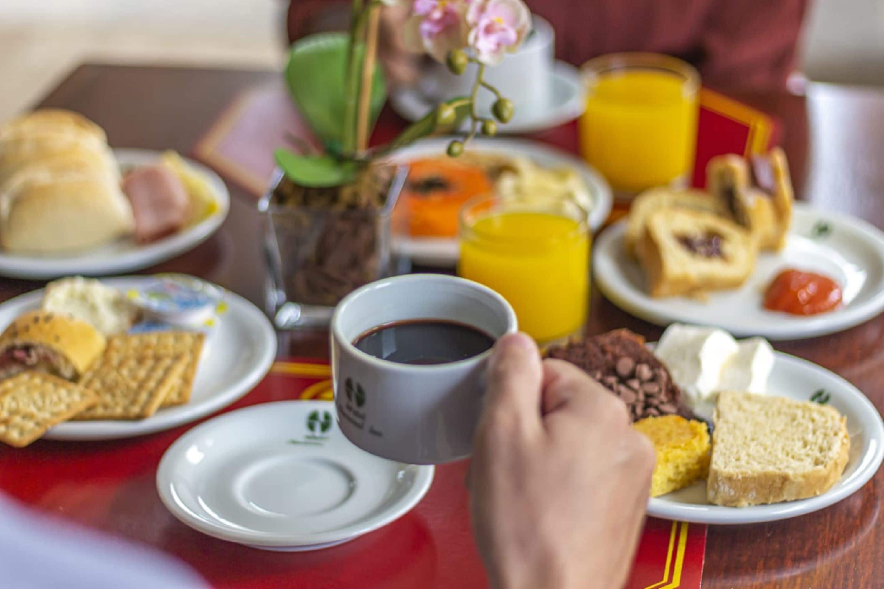 A breakfast table with various food items and a cup of coffee.