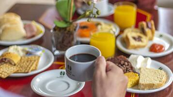 A breakfast table with various food items and a cup of coffee.