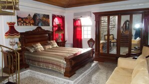 A bedroom with a wooden bed, a large mirror, a sofa, and a staircase.