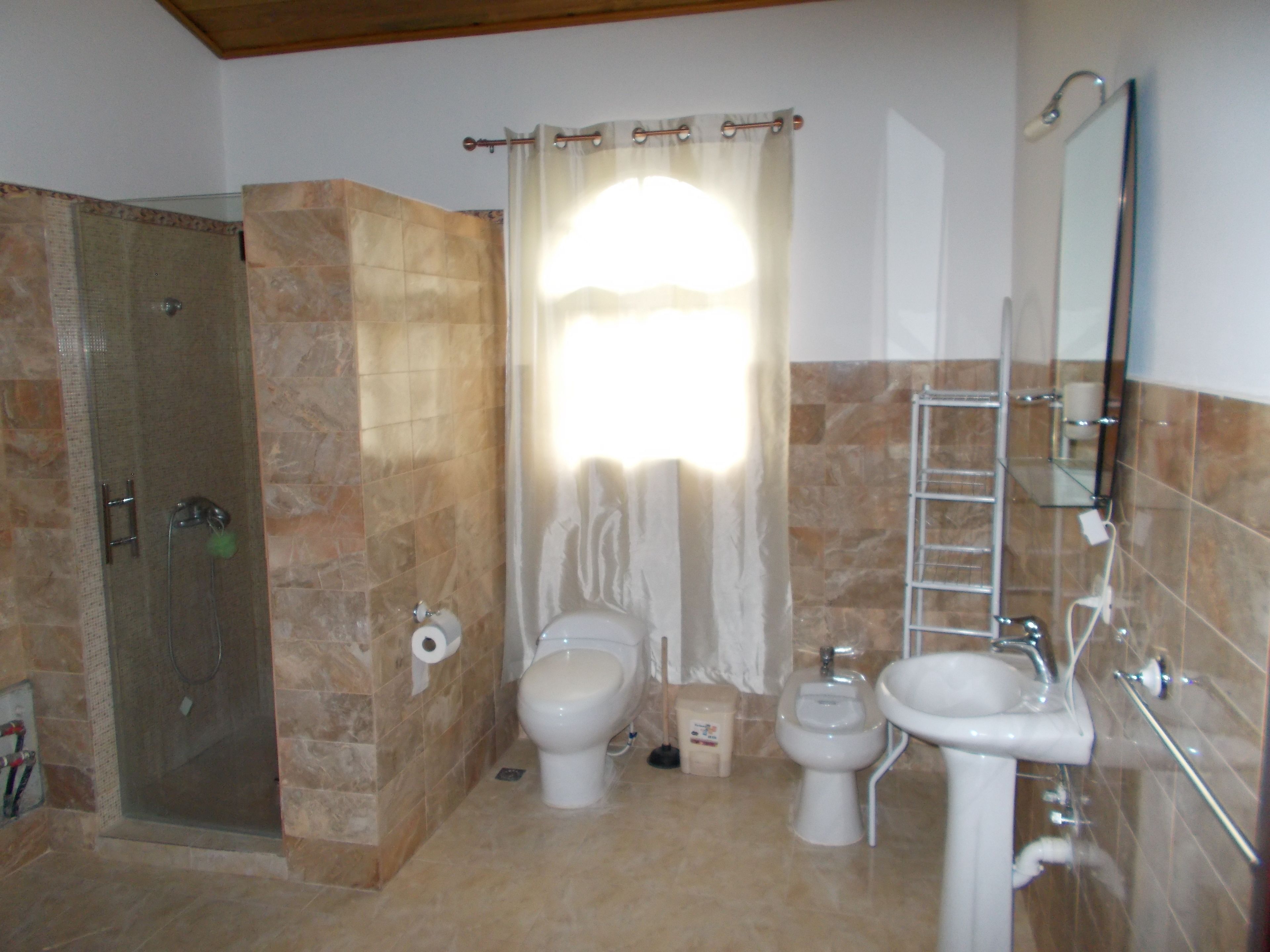 Un baño con ducha, inodoro, bidé y lavabo.