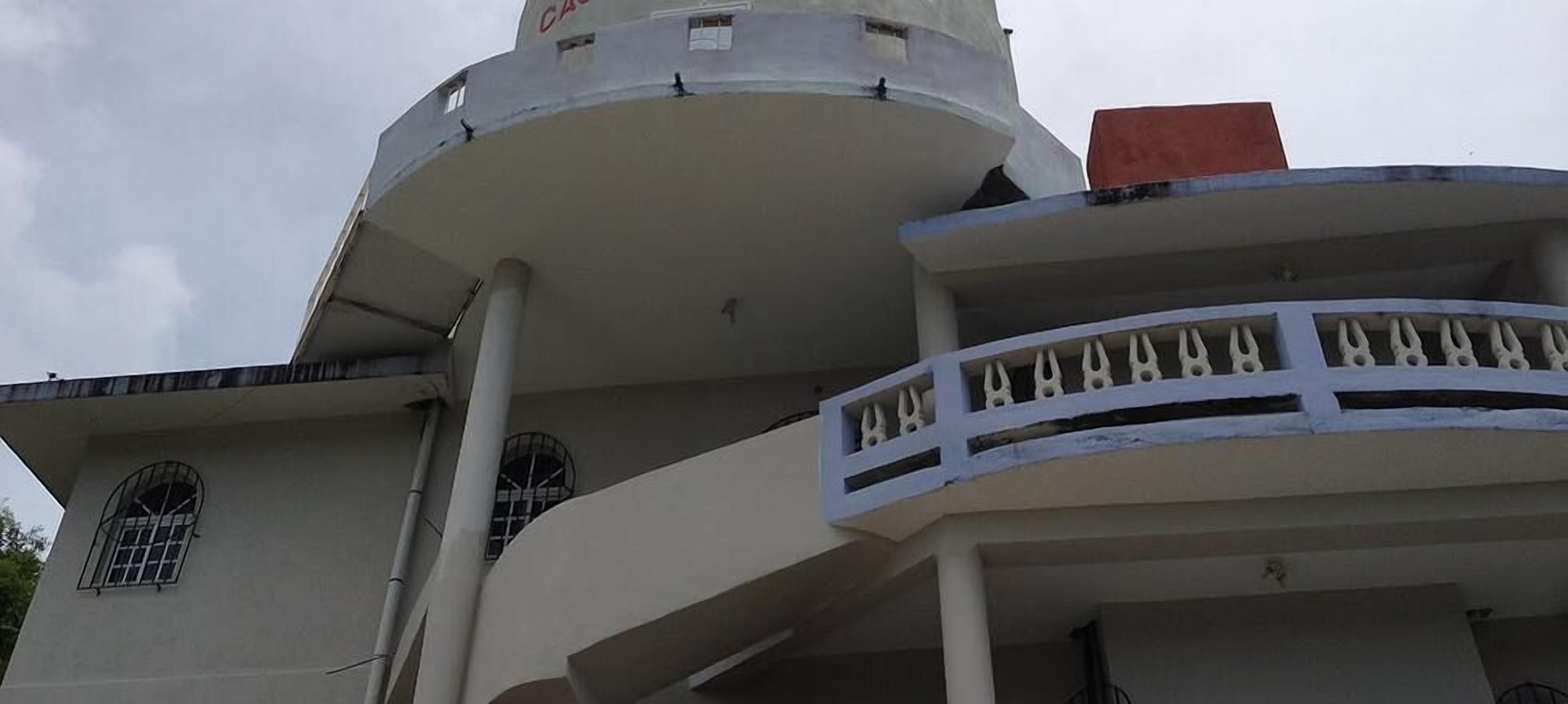 A building with a curved balcony and a cylindrical tower.