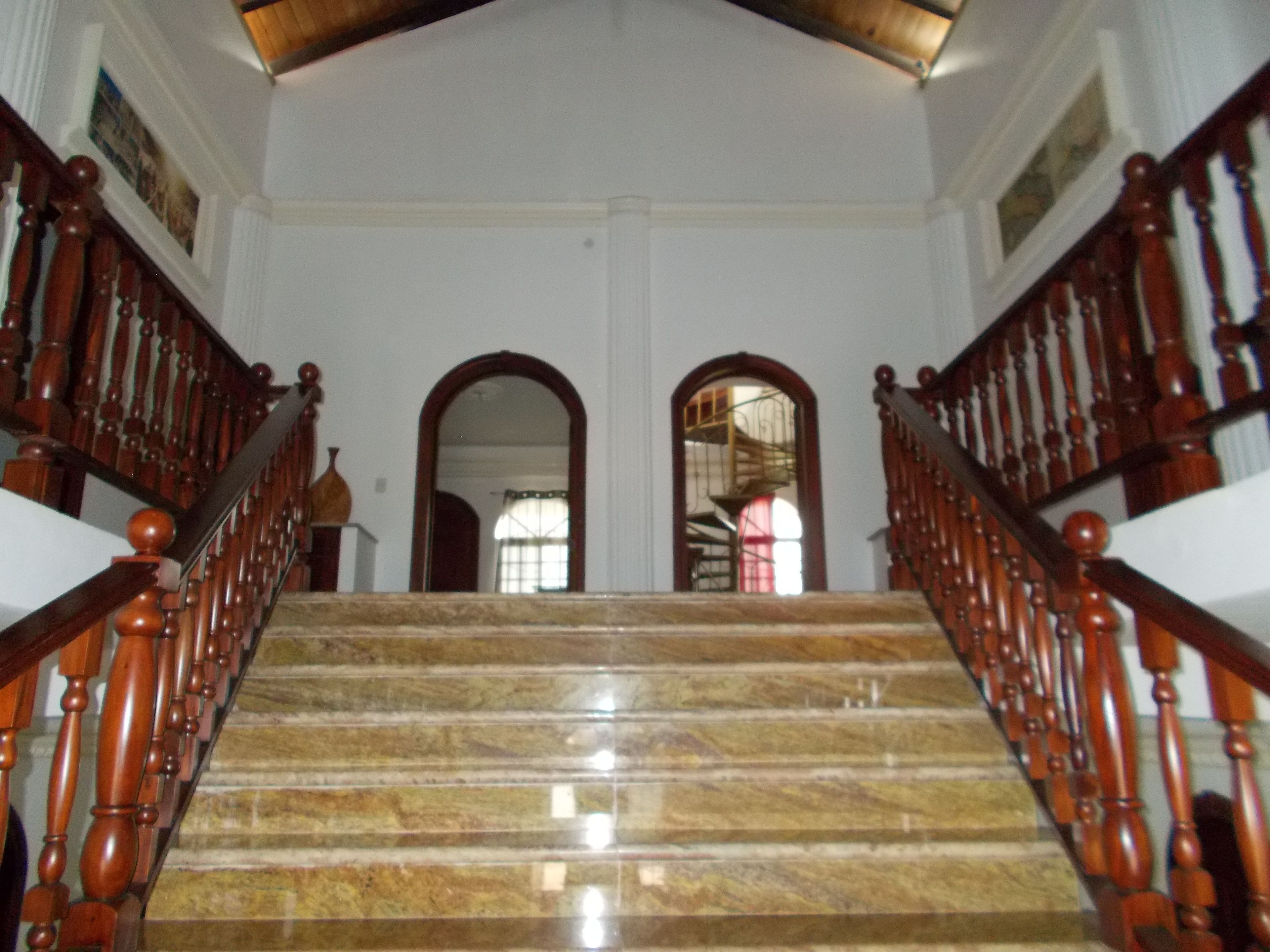 A grand staircase with marble steps and wooden balusters, leading to an upper floor.