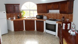 A kitchen with wooden cabinets, a stove, a microwave, and a sink.