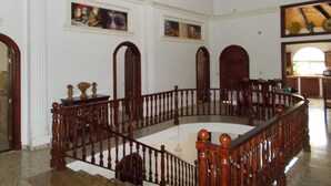 A grand staircase with a wooden railing, white walls, and a ceiling with exposed beams.