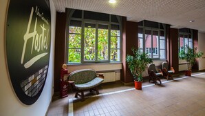 Un couloir avec une grande enseigne indiquant « Auberge de jeunesse Nouvelle Génération », un banc, des plantes en pot et un radiateur.