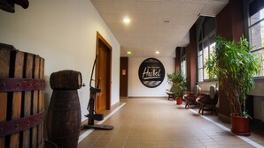 Un couloir avec un sol carrelé, des tonneaux en bois, une enseigne indiquant « Auberge de jeunesse nouvelle génération » et des plantes en pot.