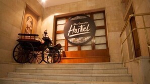 Un escalier menant à une pièce où est affichée une pancarte indiquant : « Auberge de jeunesse nouvelle génération ».