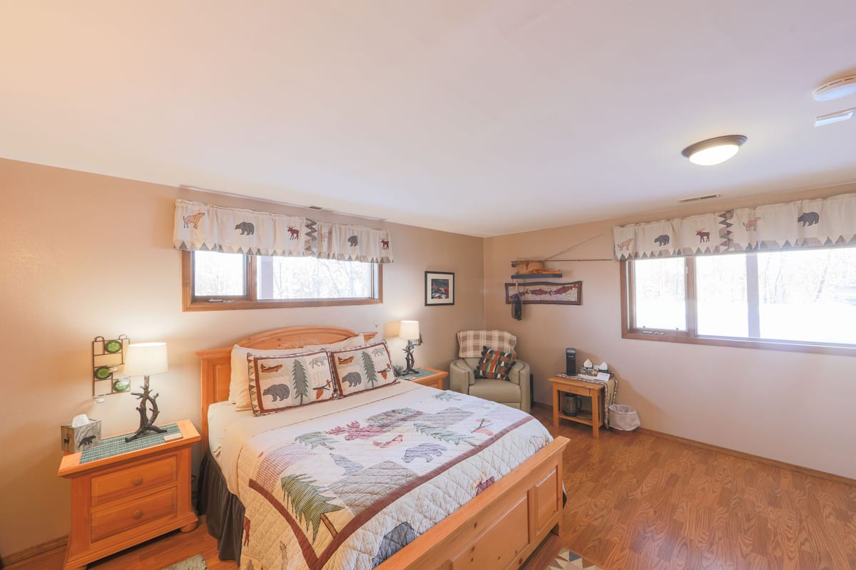 A bedroom with a wooden bed, a nightstand, a chair, and a small table.