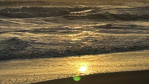 Une plage avec des vagues et un soleil couchant.