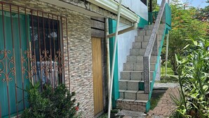 Une maison avec un escalier en pierre, un portail en métal et un chemin dallé.