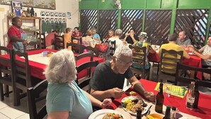 Un restaurant avec des tables et des chaises, des clients qui déjeunent ou dînent, et un menu affiché au mur.