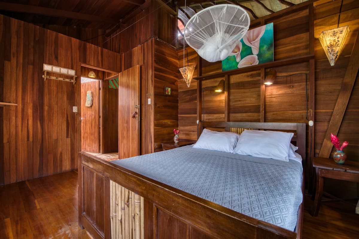 Une pièce en bois avec un lit, des murs en bois et un ventilateur de plafond.