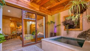 Un área de spa con jacuzzi, techo de madera y plantas de interior.