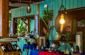 A restaurant with a wooden interior, a bar area with bottles, and a counter with various items. - Hotel Banana Azul - Adults Only (Cahuita)