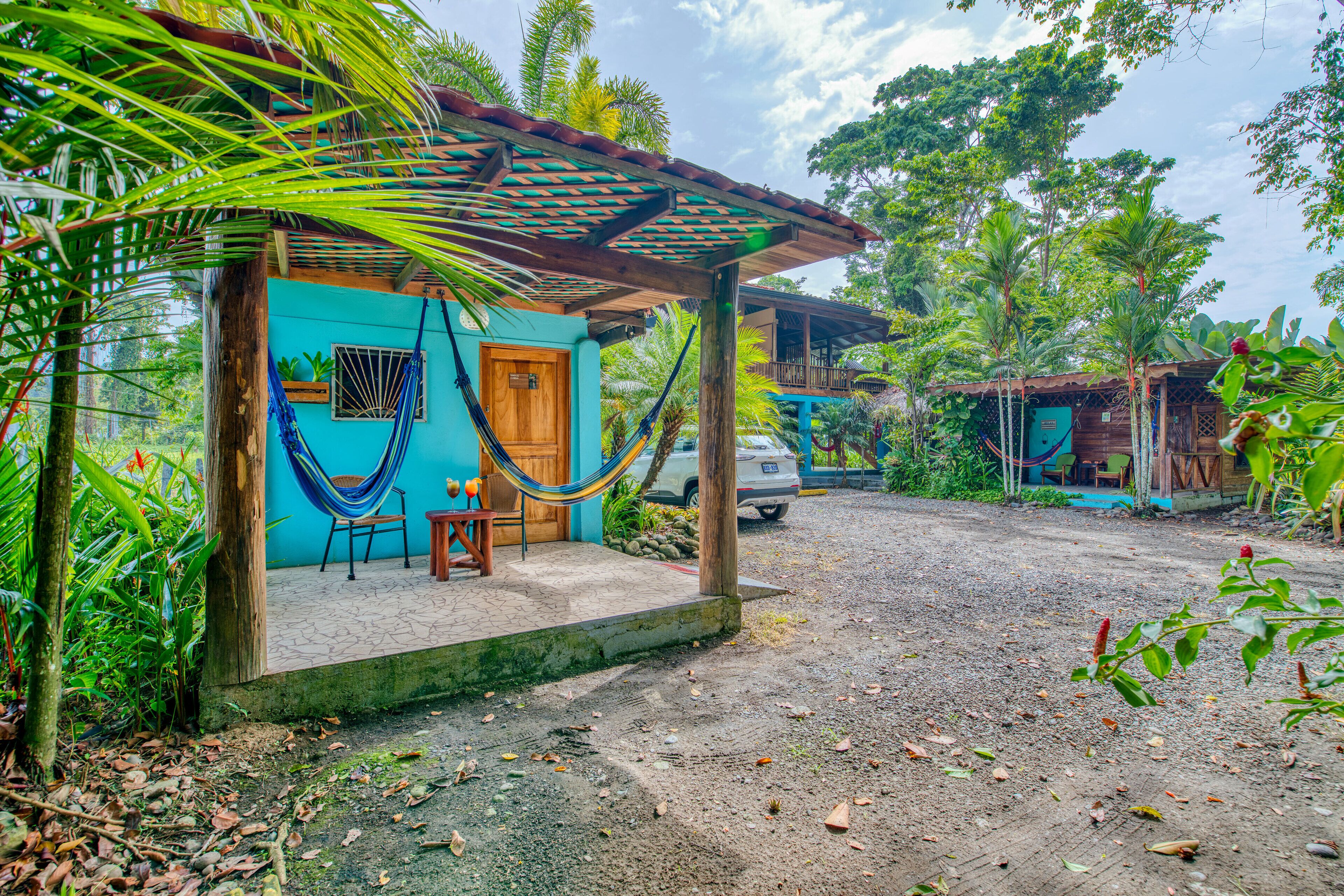 A rustic house with a wooden porch, a hammock, and a small seating area.