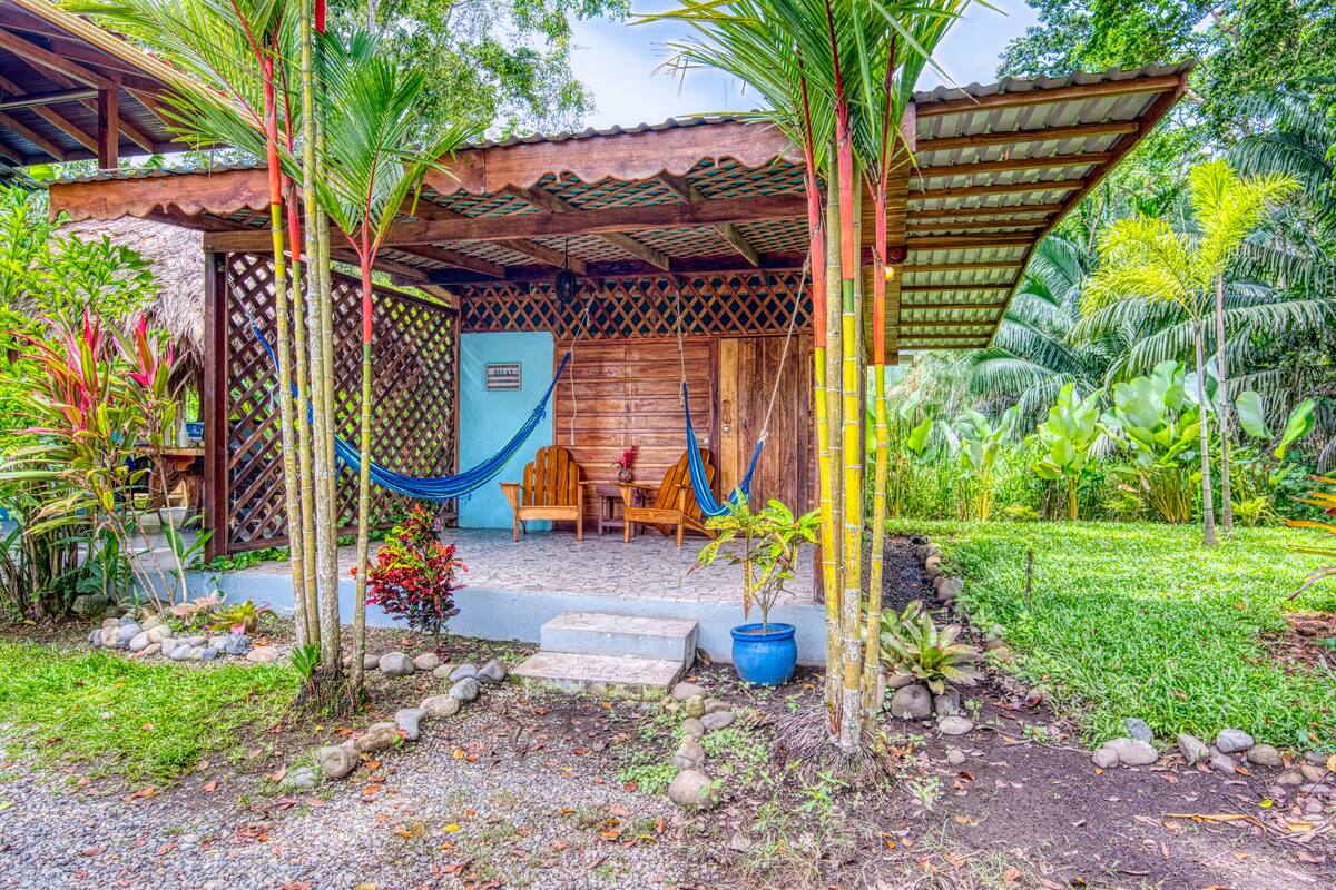 Une structure en bois avec un toit de chaume, un hamac et un petit espace de détente extérieur.