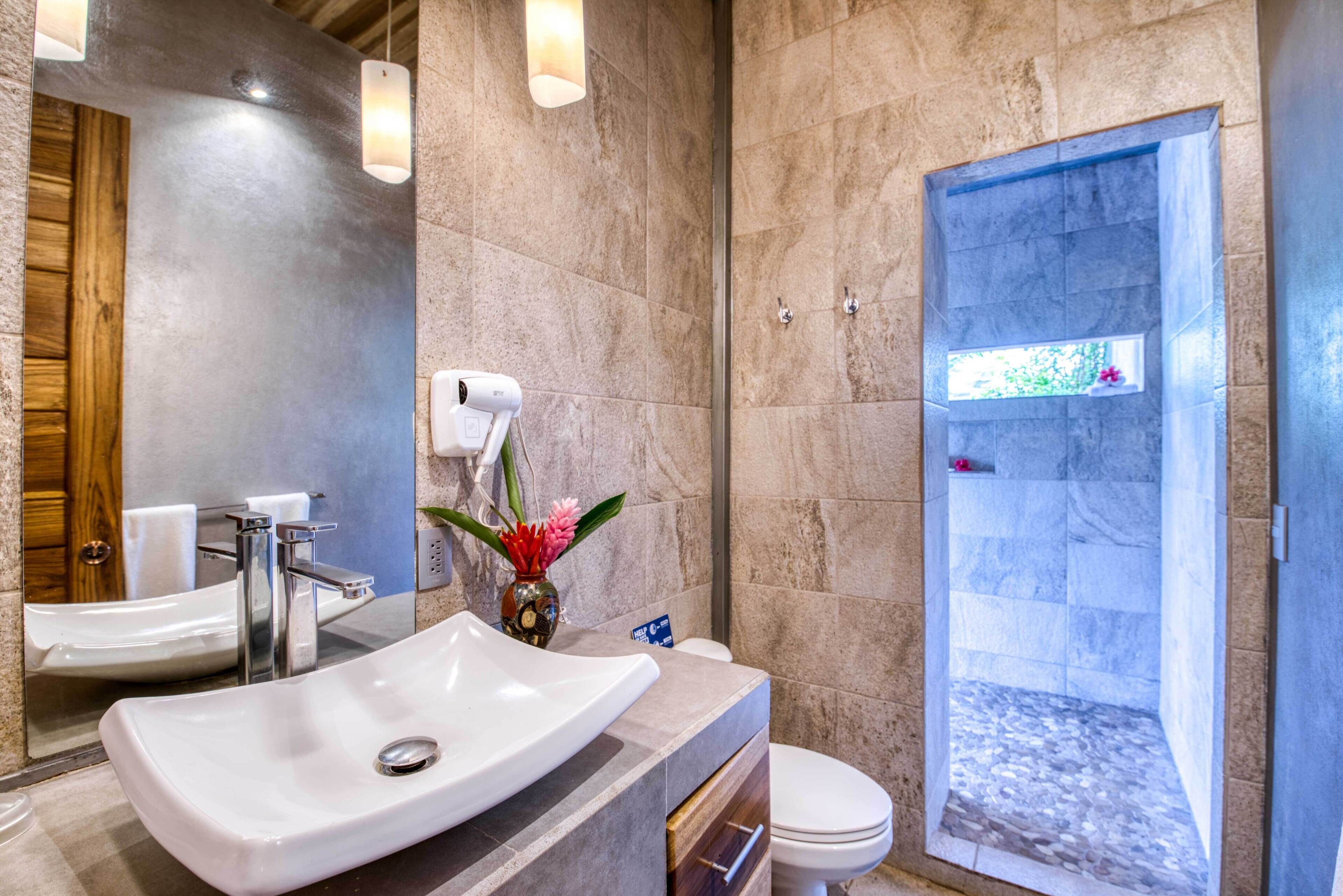 Une salle de bain moderne avec un grand lavabo, un miroir et une douche.