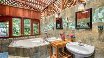 Un baño con techo de madera, dos lavamanos, una bañera grande y una pared de mosaicos.