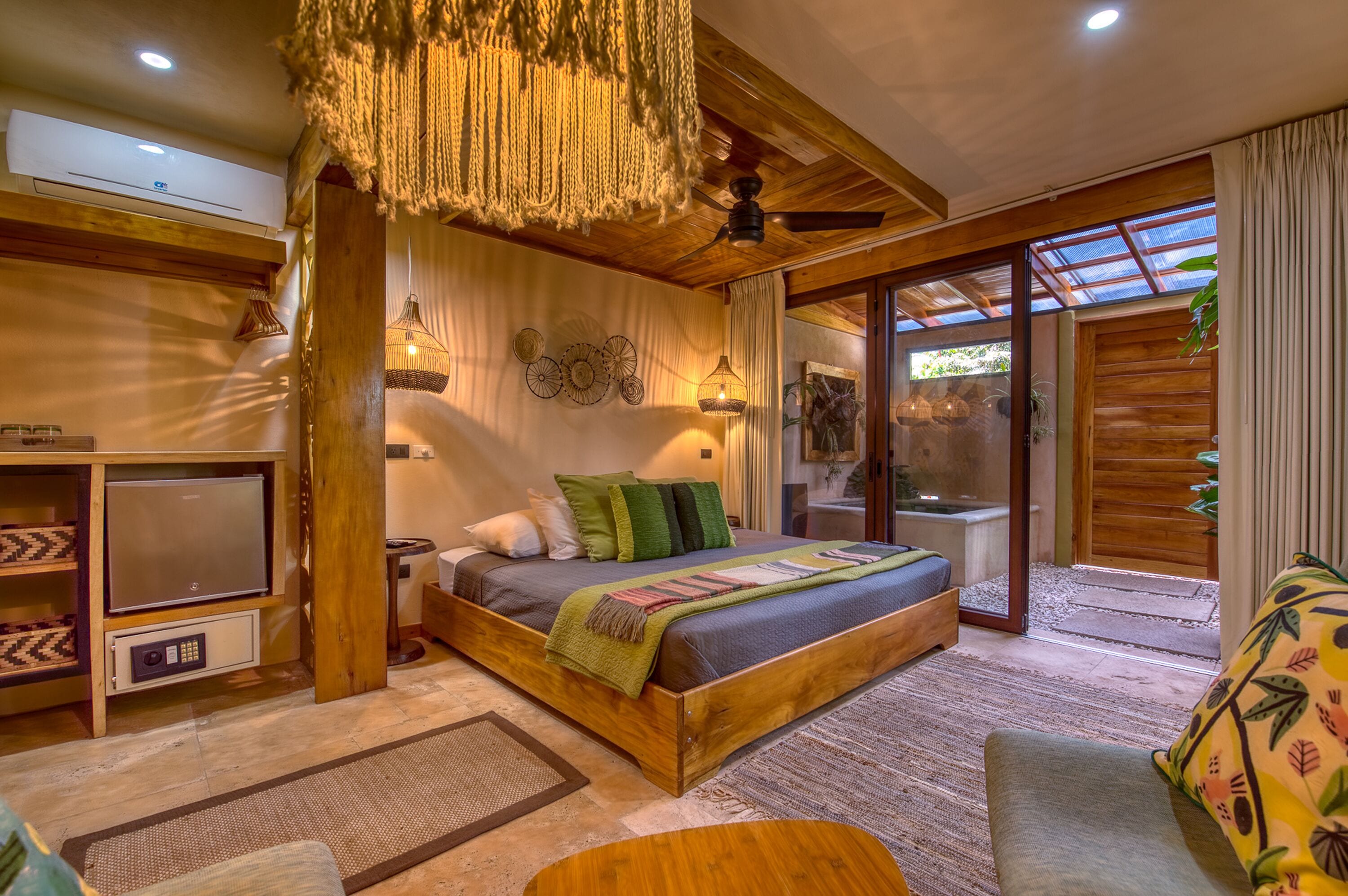 A spacious bedroom with a large bed, a ceiling fan, and a view through a glass door.