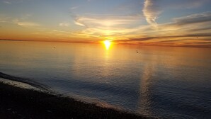 Solnedgang over et roligt vand med en klar horisont.