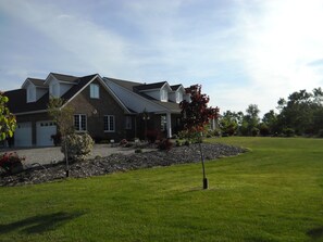A two-story house with a sloped roof, a garage, and a well-maintained lawn. - Wenzler's Landing Bed & Breakfast (Leamington)
