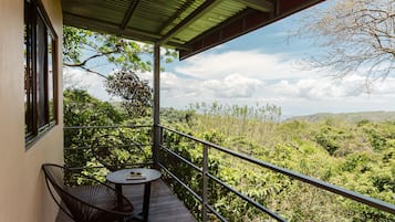 Un balcon avec une table et des chaises, donnant sur un paysage luxuriant.
