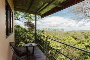 A balcony with a table and chairs, overlooking a lush landscape.