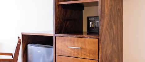 A compact wooden desk with a built-in refrigerator, drawers, and a hanging rack.