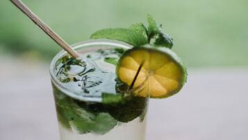 Un verre avec une paille, des feuilles de menthe et une tranche de citron vert.