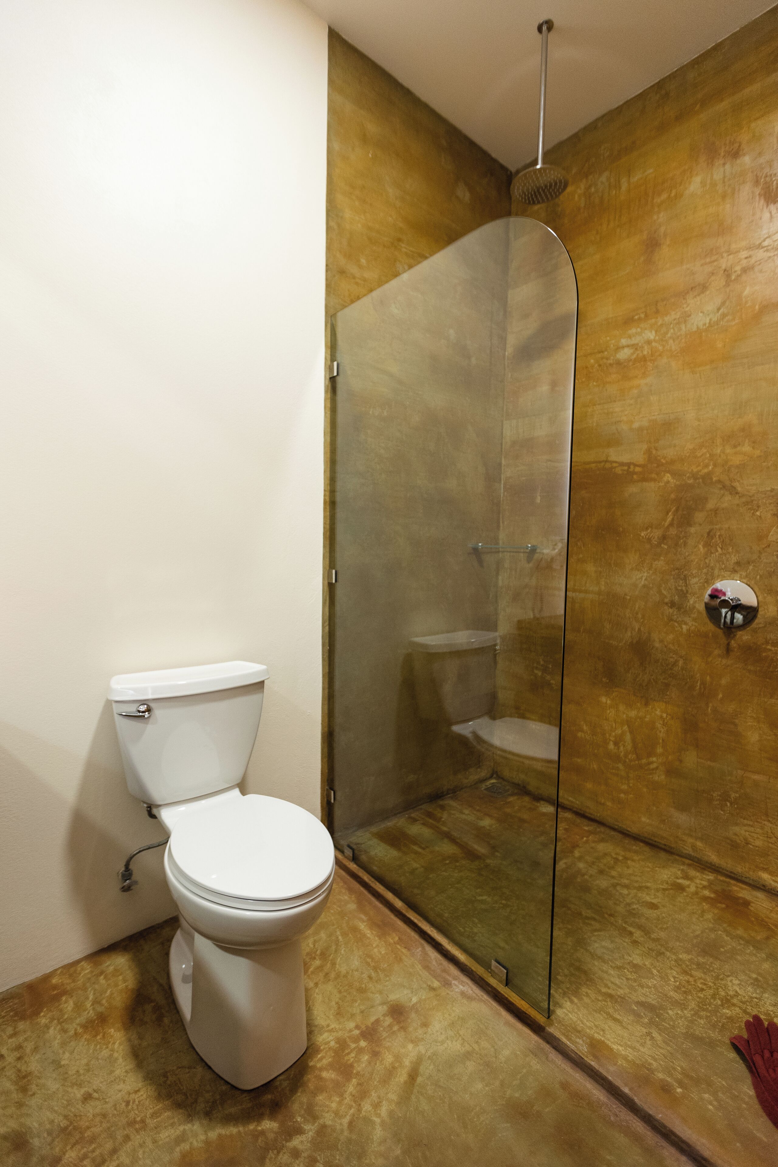 Un baño con inodoro, ducha envuelta en vidrio y pared de mármol.